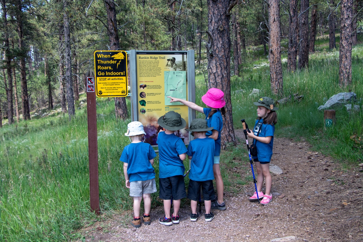 Kids reading trail information at a forest trailhead kiosk